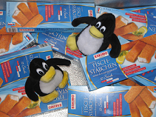 Tuxis zwischen Fischstäbchenpackungen